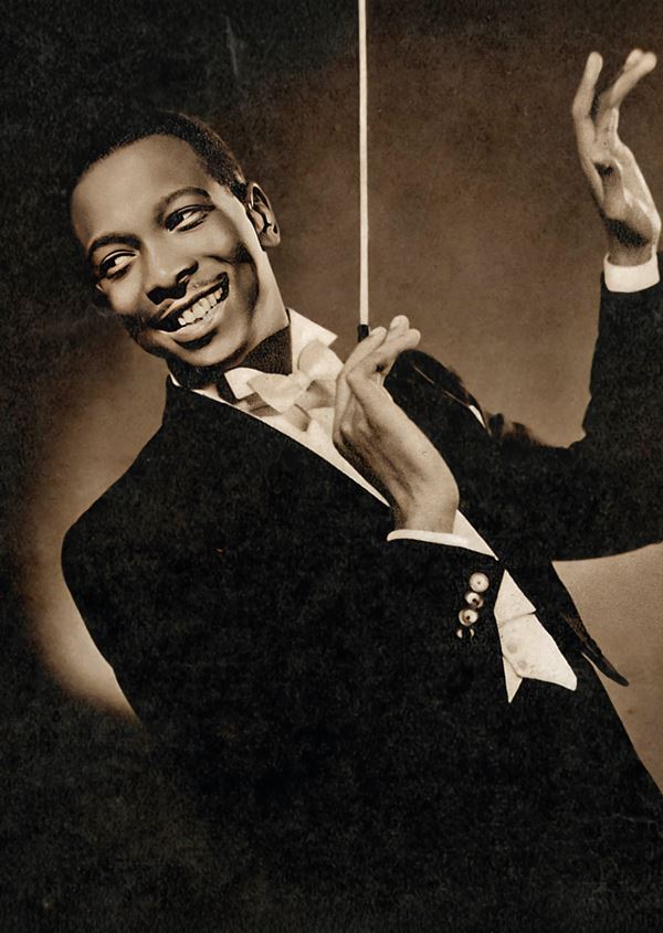 black and white photo of a young black man dressed in white tie, holding a conductors baton